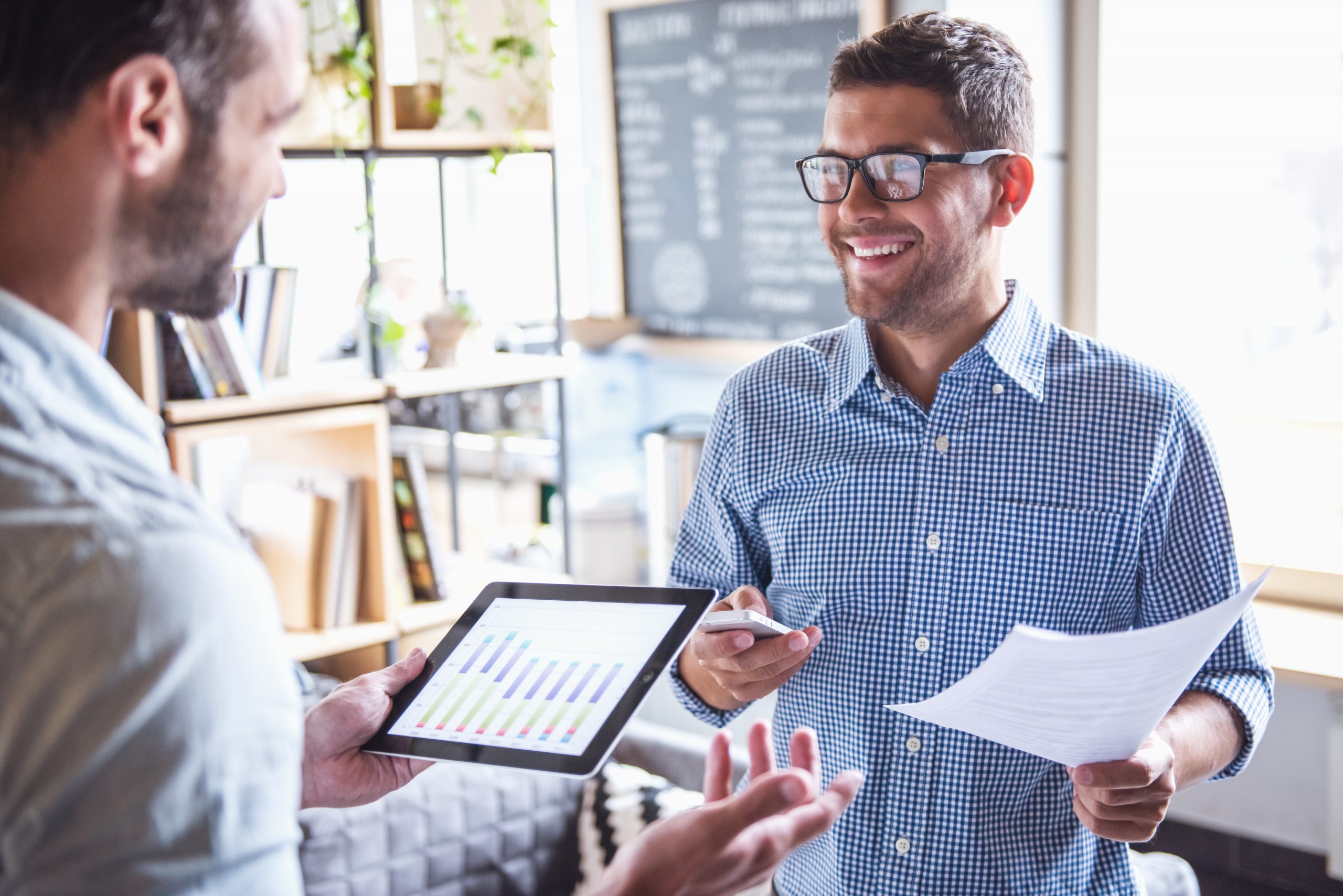 Handsome businessmen are using gadgets, talking and smiling while working in office